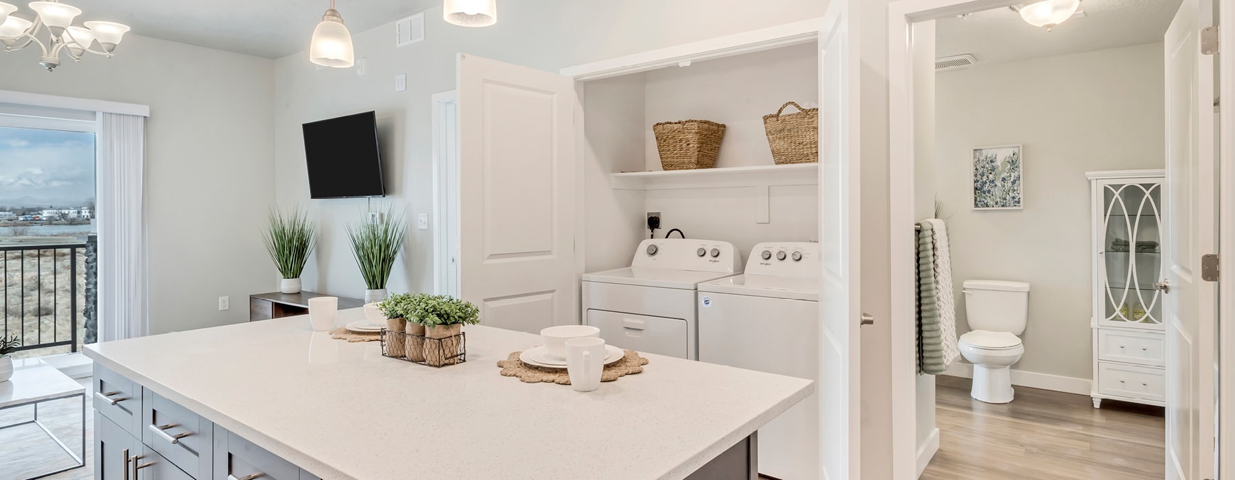 pendant lighting over kitchen island adjacent to laundry closet with side-by-side washer/dryer units
